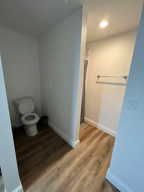 An interior photo showing a bathroom with a toilet and shower area.