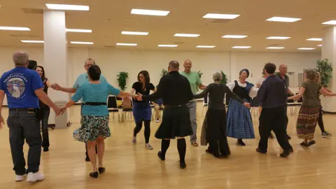 A group of people dancing in a circle inside a hall.