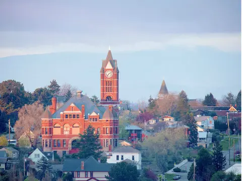 An elevated exterior view of a town with a large red brick courthouse and clock tower.