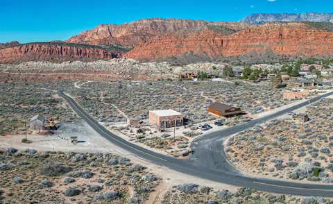 An aerial view of buildings and a desert landscape with red rock mountains in the background.