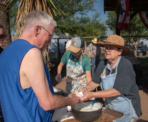 People serving food outdoors at a community event.