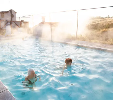 People swim in an outdoor steaming pool.