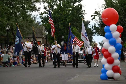 A color photograph of people carrying flags down a street during a parade.