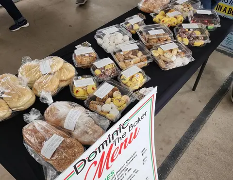 A table laden with various baked goods and a menu sign.
