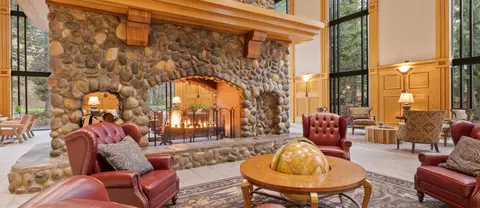 A spacious lounge features a large stone fireplace and comfortable armchairs.