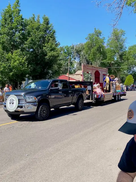 A pickup truck pulls a parade float along a street.