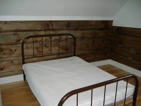 A bedroom with a metal frame bed and log walls.