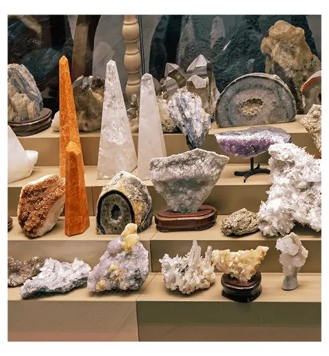 A display shelf holds a collection of various crystals, geodes, and minerals.