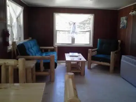 A photo showing the interior of a cabin with wooden furniture.