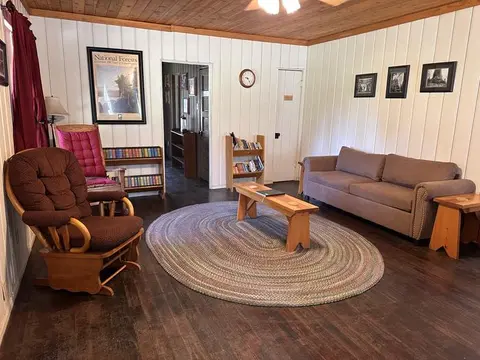 A cozy interior room with a sofa, armchair, and braided rug.