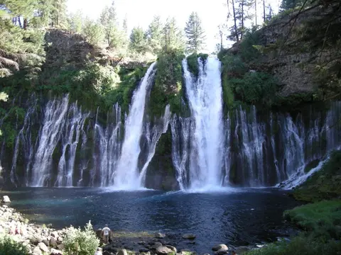A large waterfall flowing into a pool of water surrounded by trees and rocks.