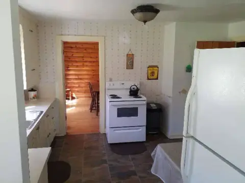 A photograph showing the interior of a kitchen with a white stove and refrigerator.