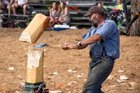 A man chops a block of wood with an axe.