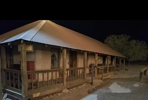 An old historic building with a porch and corrugated metal roof at night.