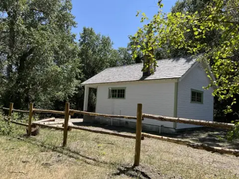 A small white building with a wooden fence in the foreground.