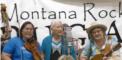 A band performs in front of a banner.