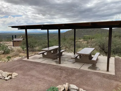 A covered picnic shelter in a desert landscape under a cloudy sky.