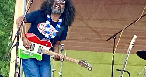 A musician plays a guitar on a stage.