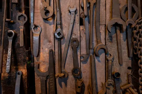 A collection of old metal tools hanging on a wooden wall.