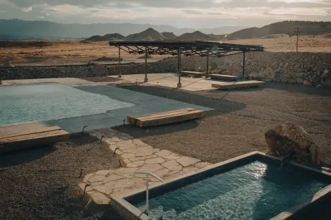 An outdoor pool area in a desert landscape with mountains in the background.