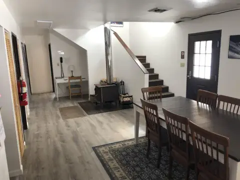 An interior view showing a dining area, a wood stove, and stairs.