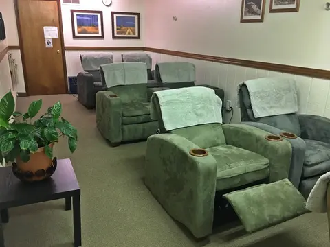 An interior room features several comfortable armchairs and a potted plant.