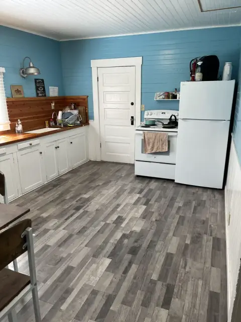 A kitchen with blue walls, white cabinets, a stove, and a refrigerator.