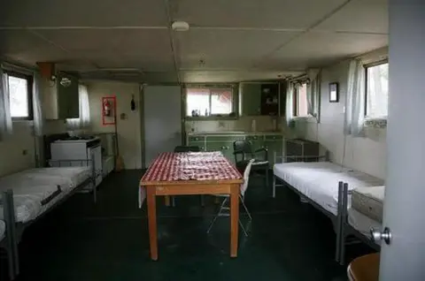 A photo showing the interior of a room with beds and a dining table.