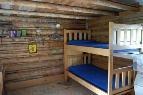 An interior view of a rustic log cabin bedroom with bunk beds.