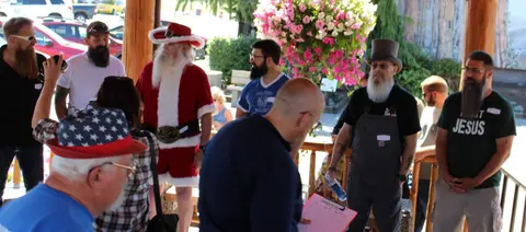A group of bearded men, including one dressed as Santa Claus, gathered on a porch.