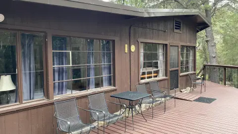 A wooden cabin exterior with a deck and outdoor seating.