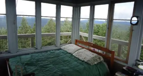 Interior view of a small room with large windows overlooking a forest and mountains.