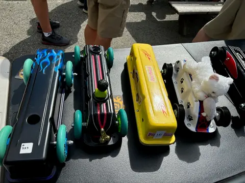 Several decorated toy cars sit on a table outdoors.