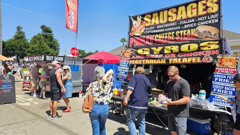 People waiting at outdoor food booths during an event.