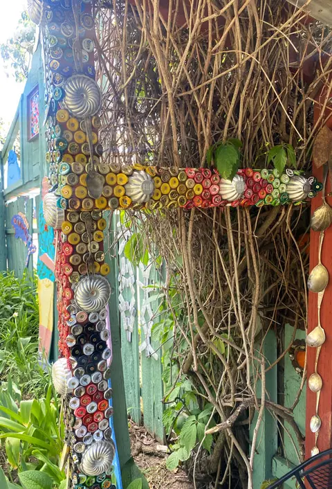 An exterior view of a structure decorated with bottle caps and kitchen utensils.