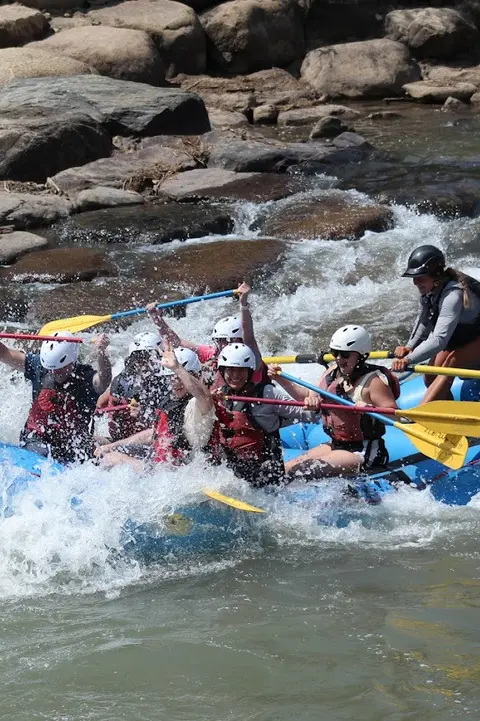 A group of people white-water rafting on a river through rapids.