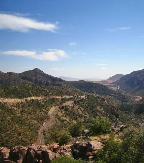 A winding road through a mountainous landscape under a blue sky.