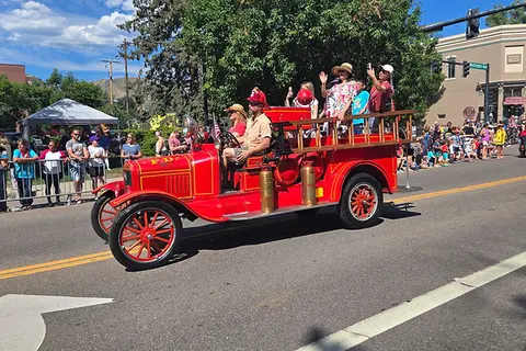 An antique fire truck driving in a parade.
