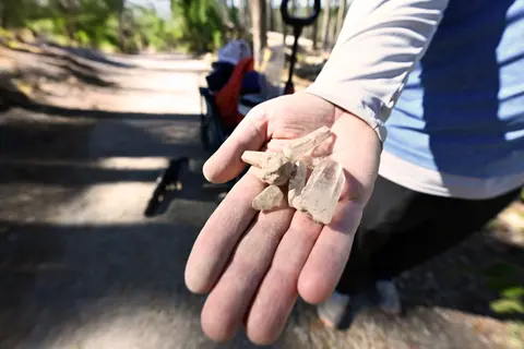 A person holds several crystals in their hand outdoors.