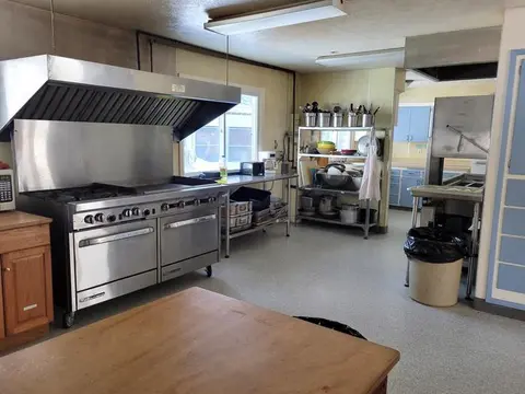 A commercial kitchen with stainless steel equipment and a large range hood.