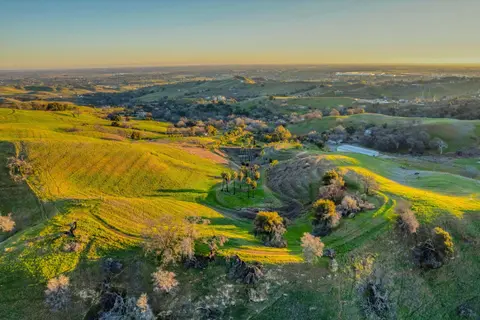 An aerial view of green rolling hills and valleys at sunrise.