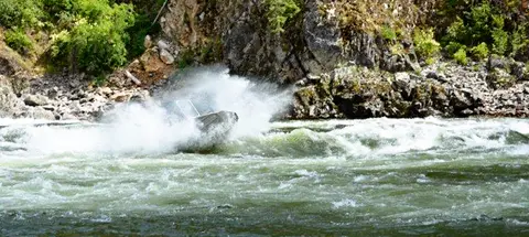 A jet boat navigating rushing rapids in a river.