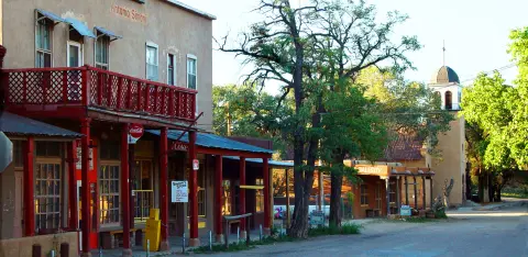 A historic street view with old buildings, a church, and trees.