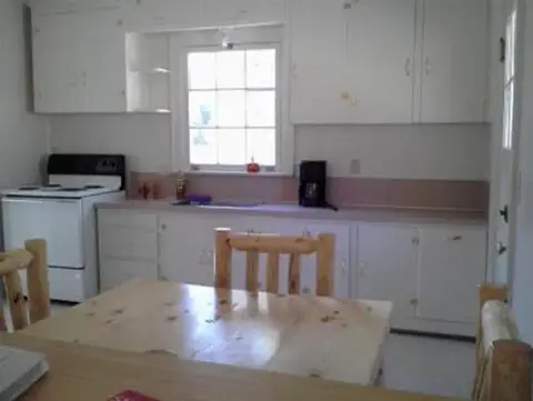 A rustic kitchen interior with white cabinets and a wooden dining table.
