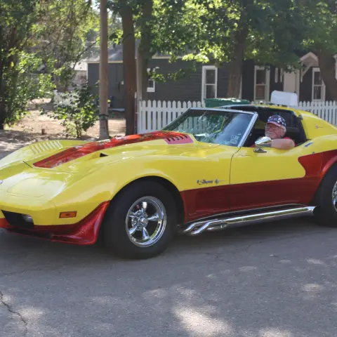 A yellow and red sports car drives on a paved street.