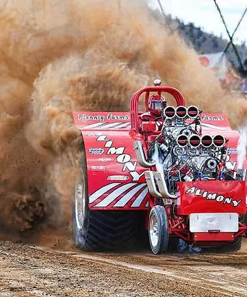 A red tractor pulls with a large cloud of dust behind it.