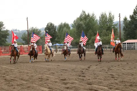 A group of horse riders carrying flags in an arena.
