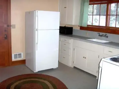 A view of the interior of a kitchen with a white refrigerator and cabinets.