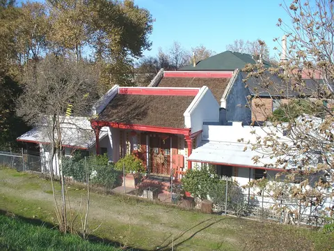 Exterior view of a traditional Chinese temple building surrounded by trees and a chain-link fence.