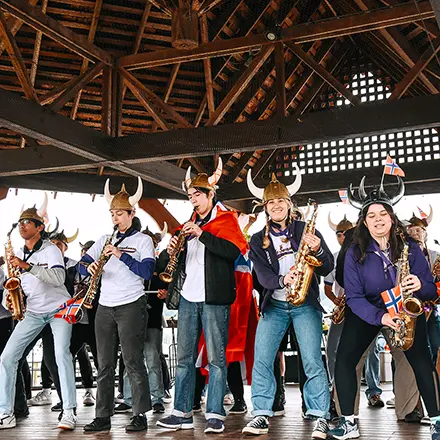 People wearing horned helmets play saxophones inside a pavilion.